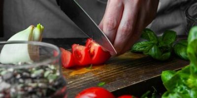 cook-cutting-tomato-wooden-board_176474-5435
